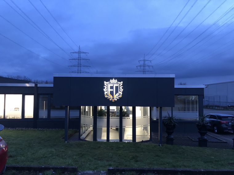 Beleuchtetes Firmenlogo &ndash; Fassadenwerbung bei Dämmerung